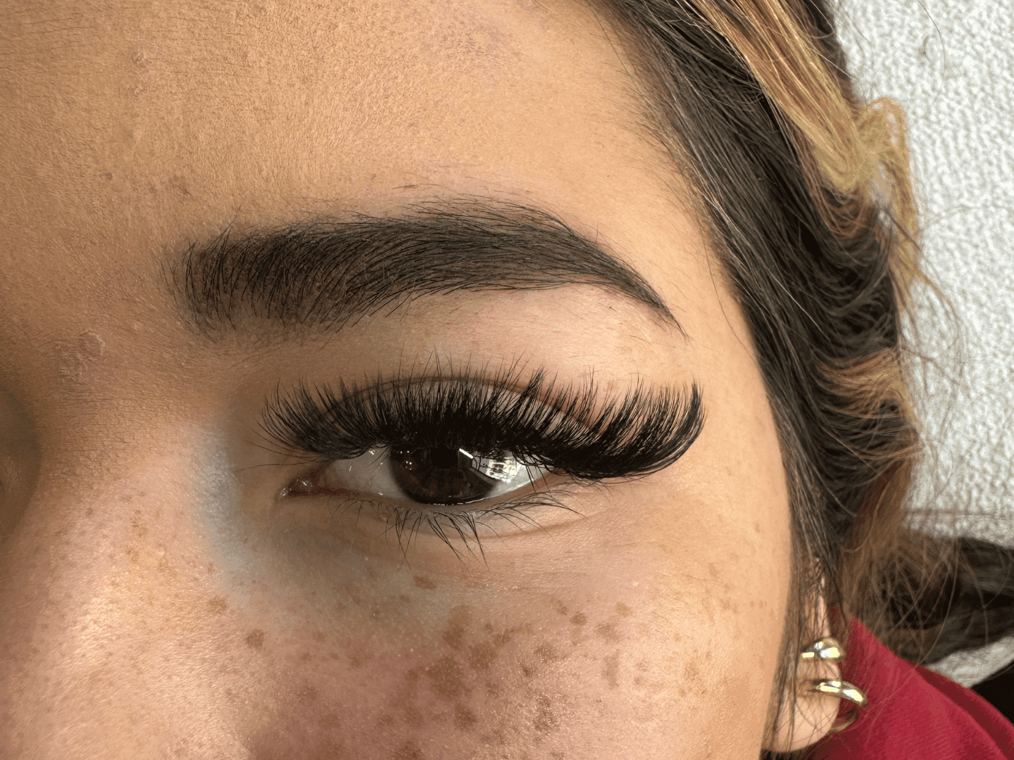 Close-up of an eye with bold makeup and long, voluminous eyelashes.