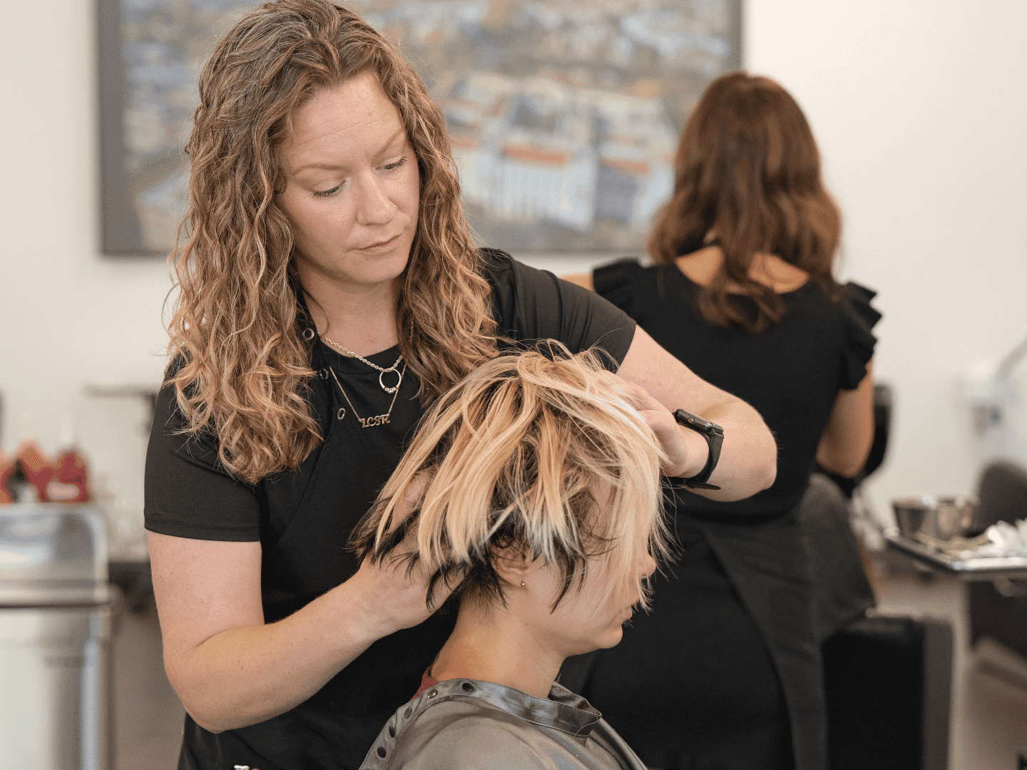 Hairstylist cutting a client's hair in a salon.