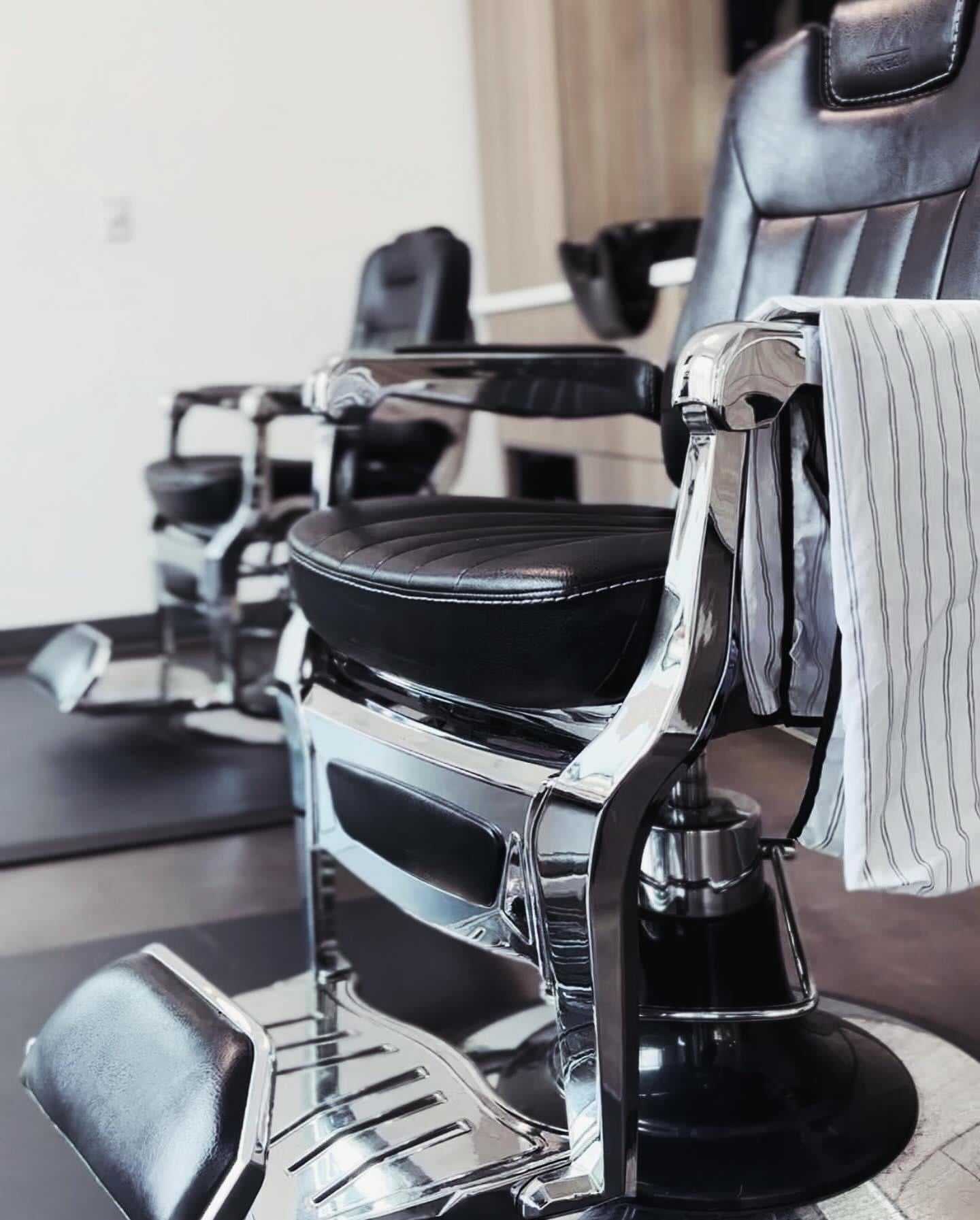 Barber chairs in a stylish salon, draped with a striped cloth.